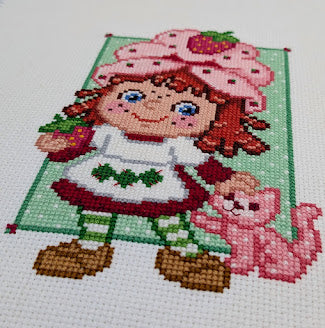 Cross-stitched design of a girl with a cat on a white background