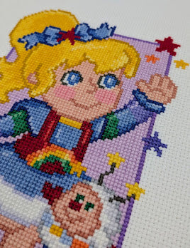 Cross-stitched design of a cartoon character with colorful rainbow details