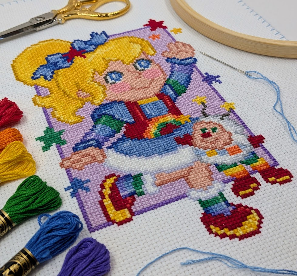 Cross-stitching project with colorful yarn and scissors on a white fabric background