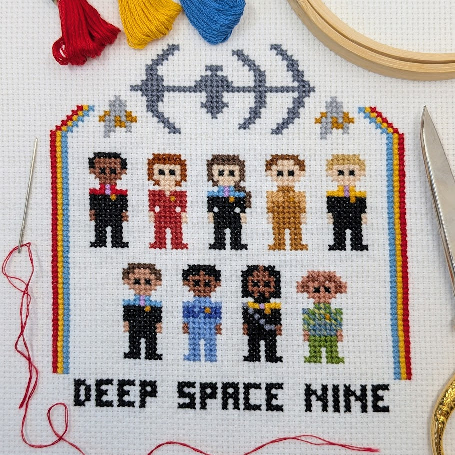 Cross-stitched pattern of characters from science fiction series with colorful thread and embroidery tools.