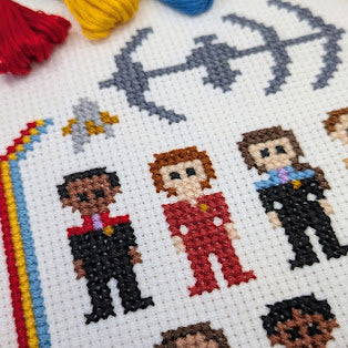 Cross-stitched characters inspired by a famous science fiction franchise on a white fabric background.