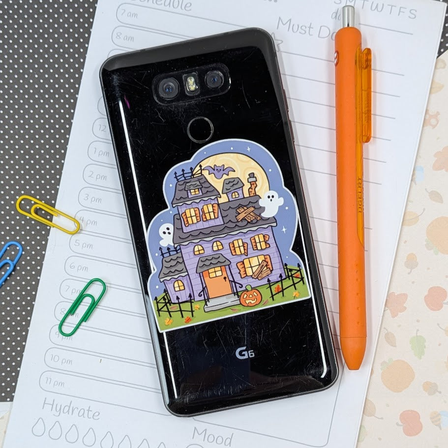 Display phone with Halloween sticker on a planner page with stationery items.
